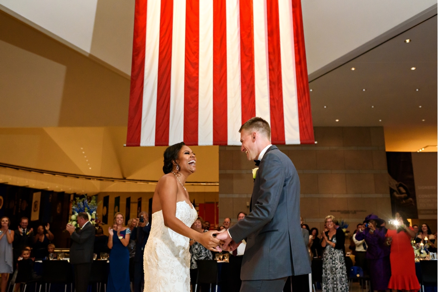 A newly married couple having their first dance under the american flag at their National Constitution Center Wedding.